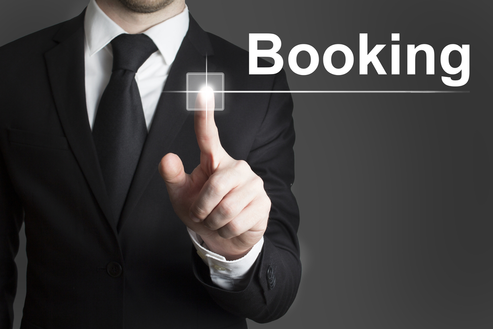 Businessman,Touchscreen,Booking A man in a suit and tie pointing to the word booking.