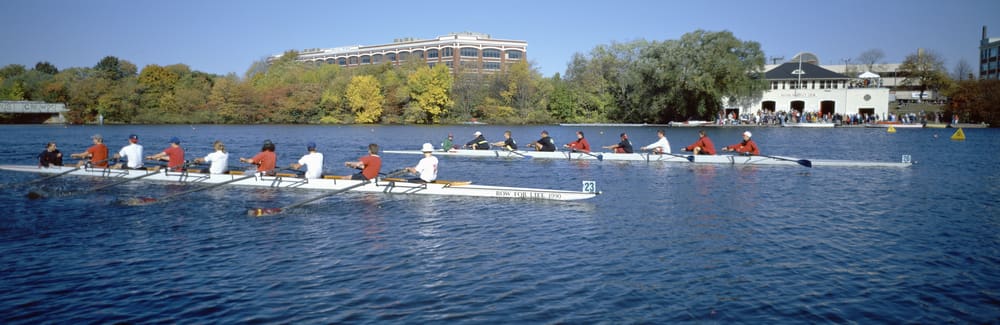 Rowers competing on a scenic river in autumn.